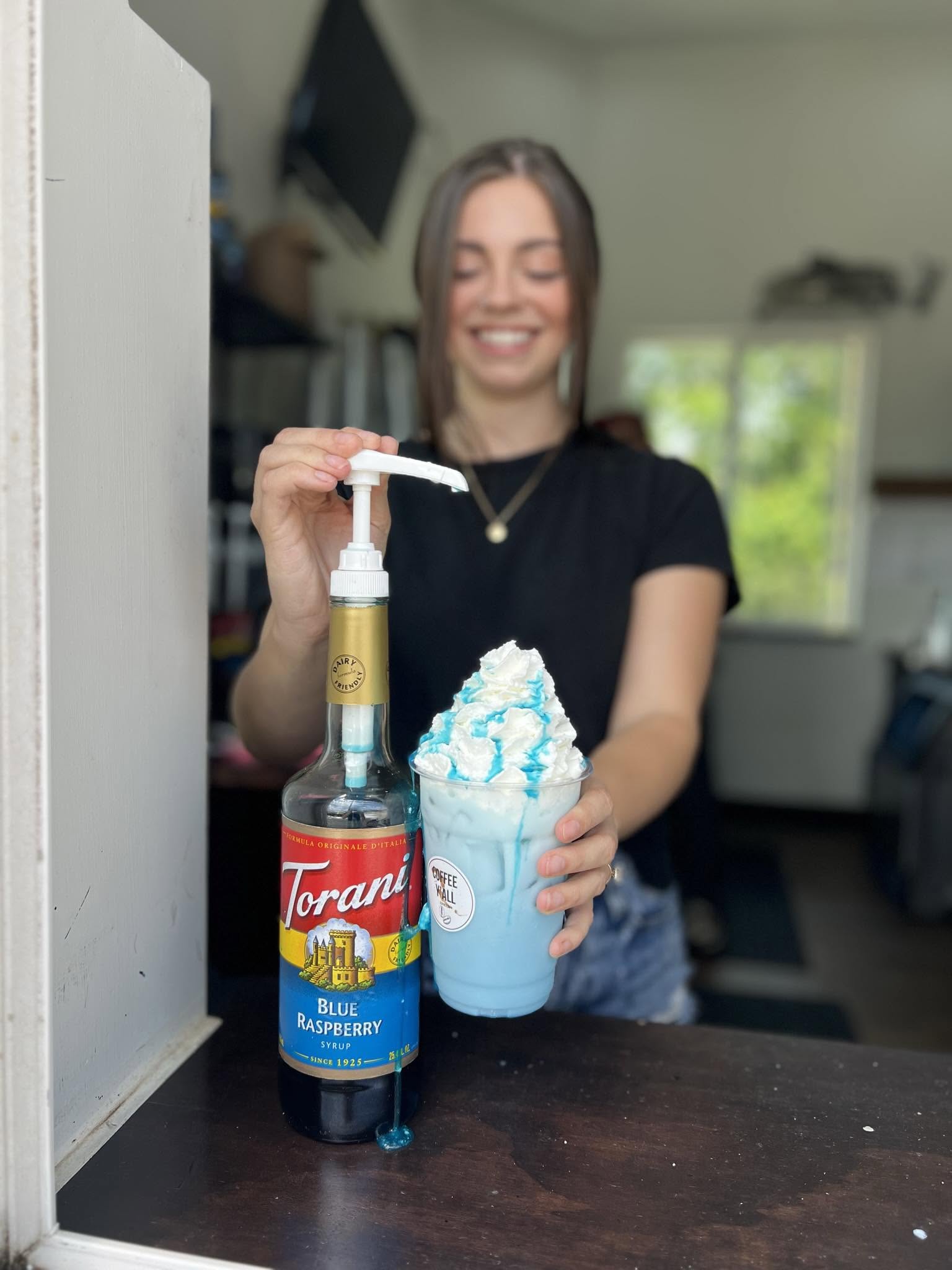 Barista pumping blue raspberry syrup over a whipped drink