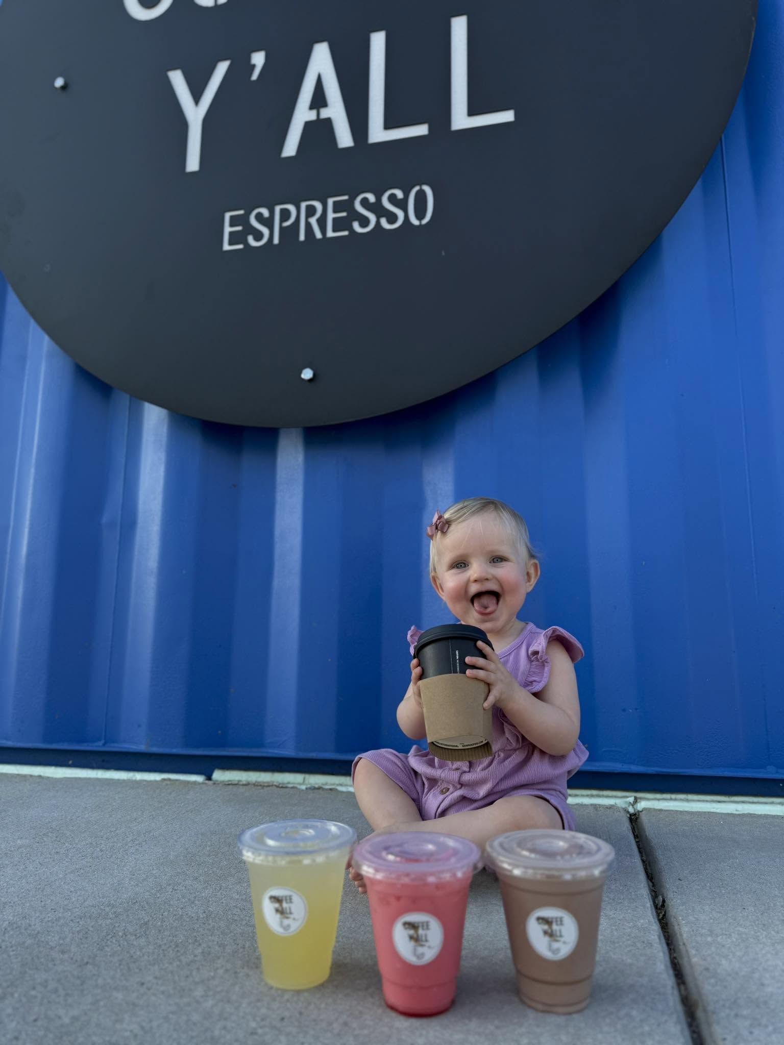 Toddler with a hot cup next to three smoothies