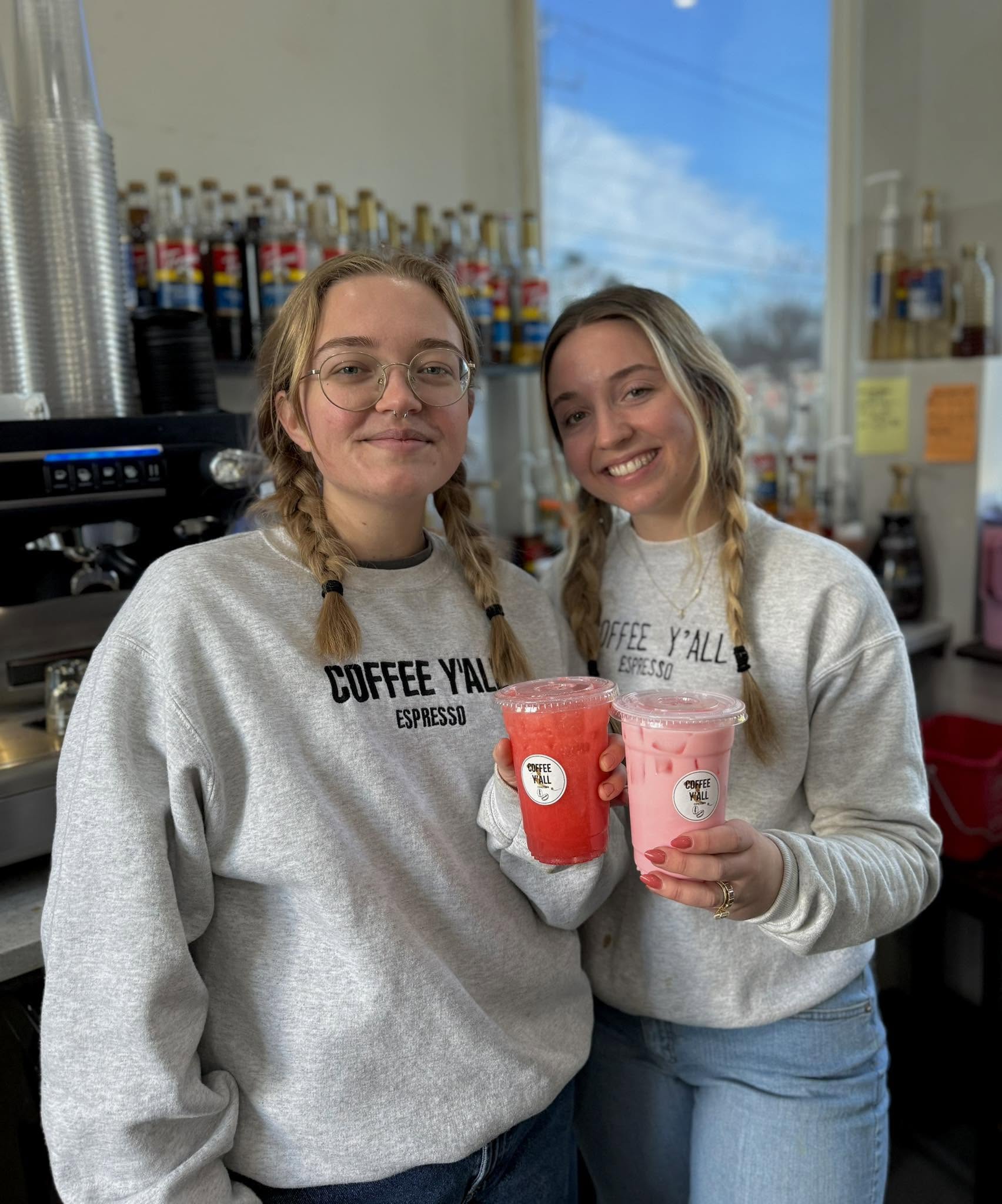 Baristas holding bright red and pink energy drinks