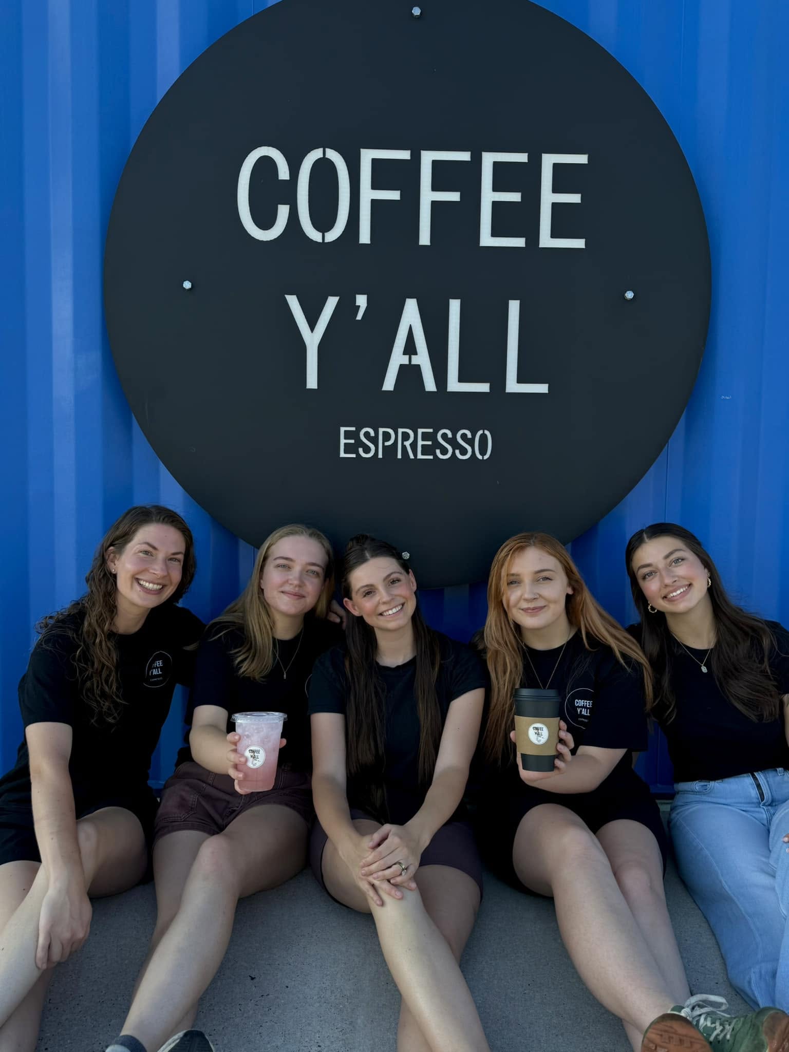 The Coffee Y'all crew under the shop sign